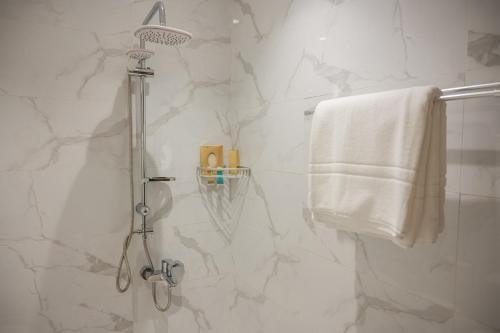 La salle de bains est pourvue d'une douche et d'une serviette blanche. dans l'établissement ابات بارك Abat Park, à Al Baha