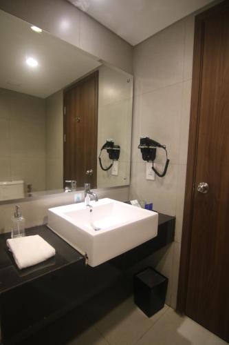 a bathroom with a white sink and a mirror at BeSS Mansion Hotel Surabaya in Wonocolo