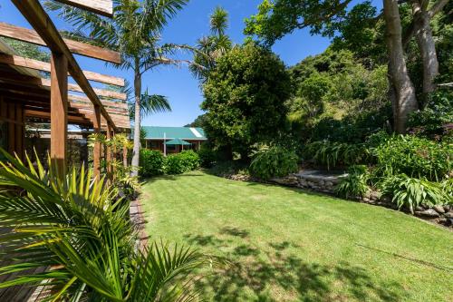 a garden with a lawn in front of a house at Aotea Lodge Great Barrier in Tryphena