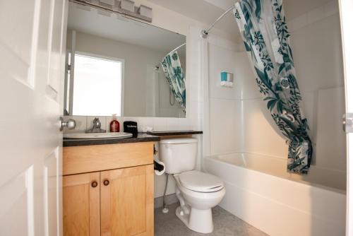a bathroom with a toilet and a tub and a sink at Renovated Chalet at Mystic Springs, Mountain Views, Pets Welcome! in Canmore