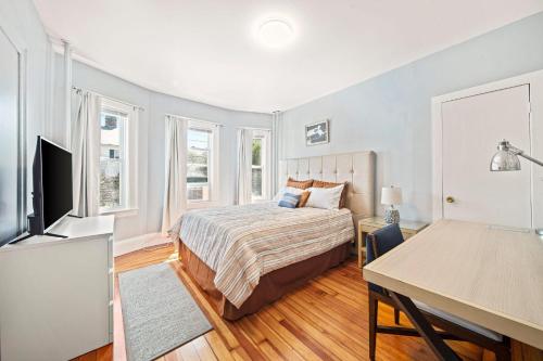 a bedroom with a bed and a desk and a television at Cozy Up in 5BR Apt Near Charming Oak Square in Boston