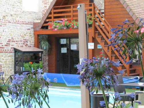 un patio con flores púrpuras y una terraza de madera en Suite Appart'Hôtel La Loggia By M Spa, en Deauville