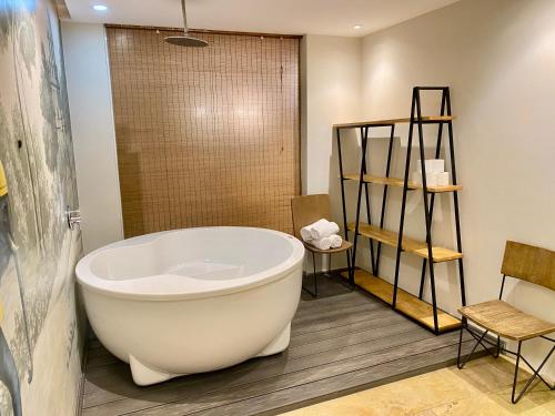 a bathroom with a large bath tub and a chair at The Palmian City Center Serviced Apartment in Ho Chi Minh City