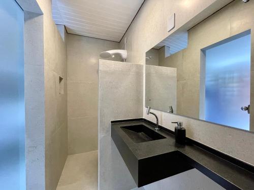 Bangalô de Madeira em Condomínio de Praia في كامساري: حمام مع حوض ومرآة كبيرة