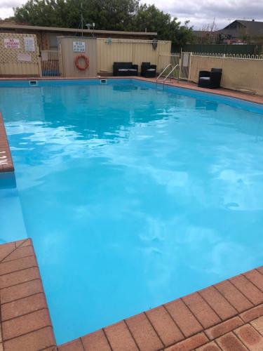 een groot zwembad met blauw water bij Ringtails Motel in Busselton