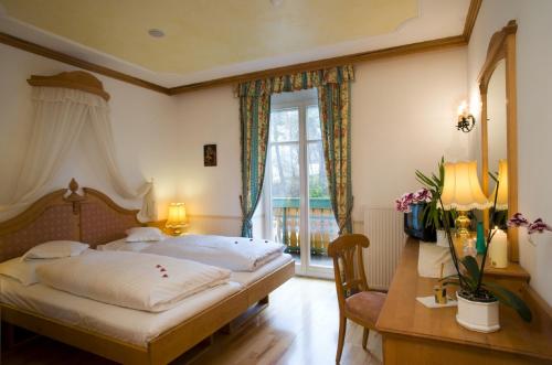 a bedroom with a bed and a desk and a window at NaturResidence Dolomitenhof in Siusi