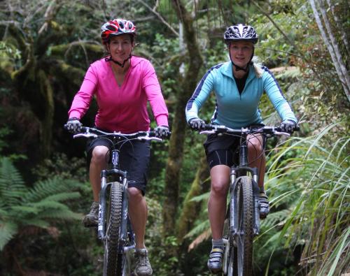 two women riding bikes down a forest trail at Snowy Waters - The Old Nurses Home in Raetihi