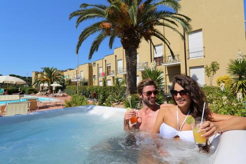 a man and woman in a swimming pool with drinks at Residence Le Acacie in Capoliveri