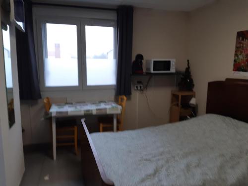 une chambre avec un lit, un bureau et une fenêtre dans l'établissement Gîte de Bénédicte Fribourg, à Colmar