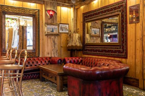 a living room with a leather couch and a mirror at Hotel Marysin Dwór in Katowice