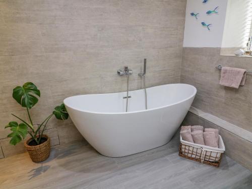 a white bath tub in a bathroom with a plant at Bay Leaf Cottage in Kirkby Stephen