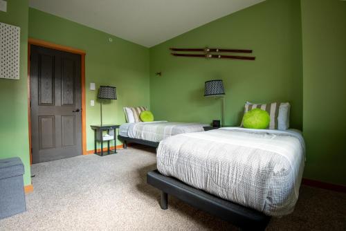 a green room with two beds and a door at Renovated Condo, 2BR, 2BA, Heated Pool, 3 Hot Tubs, Pets Welcome! in Canmore