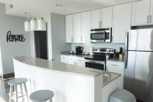 a kitchen with white cabinets and a counter with stools at Luxury Downtown Apartment with Balcony! in Greenville