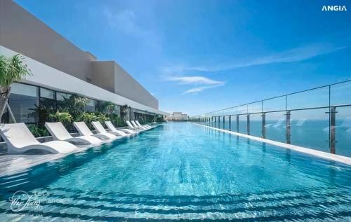 a swimming pool with white lounge chairs on a building at Phúc Khang Luxury Apartment - The Sóng Vũng Tàu in Vung Tau