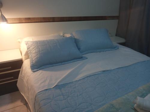 Una cama grande con almohadas azules encima. en charmoso apto Centro de Curitiba, en Curitiba
