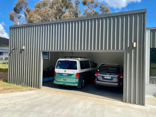 a garage with two cars parked inside of it at Jindabyne House 1, Modern 3 bedroom home, alpine views & fireplace in Jindabyne