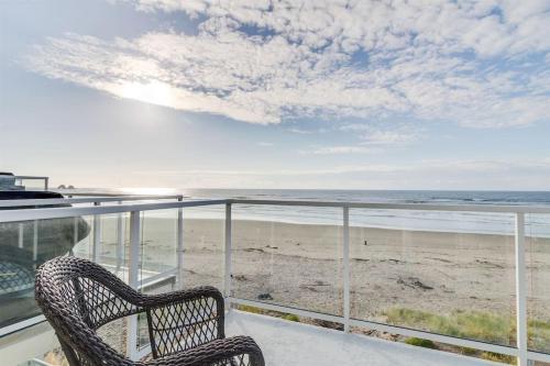 a wicker chair sitting on a balcony overlooking the beach at Rockaway beach vibes,Waterfront Oceanfront Rockaway Beach House near Downtown,WIFI, Washer Dryer in Rockaway Beach