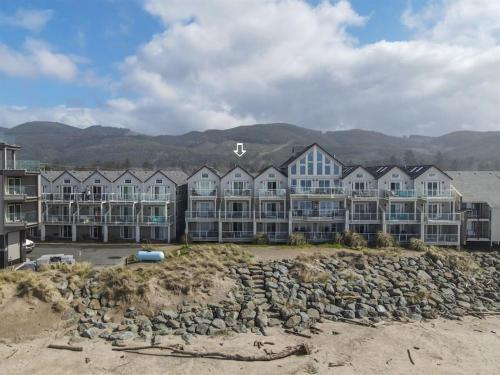 a row of houses on a beach with mountains in the background at Rockaway beach vibes,Waterfront Oceanfront Rockaway Beach House near Downtown,WIFI, Washer Dryer in Rockaway Beach