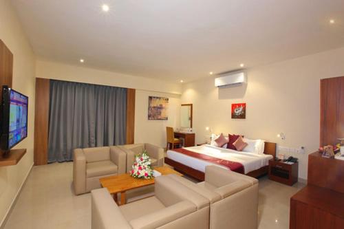 um quarto de hotel com uma cama e uma sala de estar em JK Park Residency em Cananor