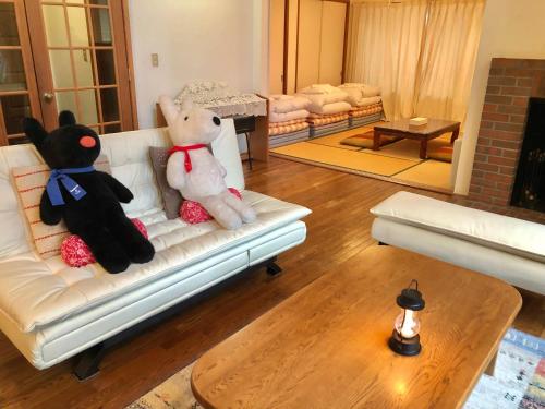two teddy bears sitting on a couch in a living room at Cottage 62 Seseraginomori Kyu-karuizawa in Karuizawa