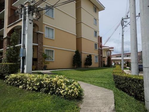 a building with a walkway next to a grass yard at Italian Inspired Tropical-Themed Studio Condo in Davao City