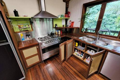 a kitchen with a sink and a stove top oven at BUTTERFLY BEND - 3 Bedroom Daintree Beach House in Cow Bay