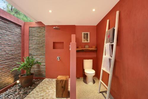 a bathroom with red walls and a toilet and a ladder at PinkCoco Gili Trawangan - Constant Surprises - for Cool Adults Only in Gili Trawangan