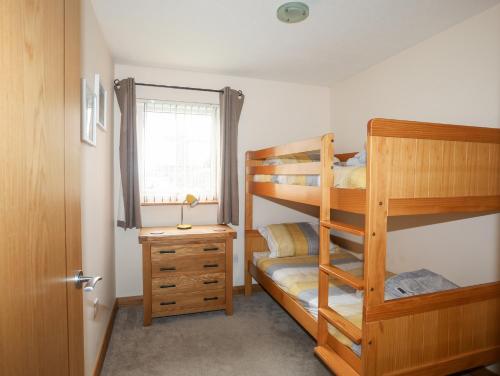 a bedroom with two bunk beds and a desk at Sandy Toes in Rhosneigr