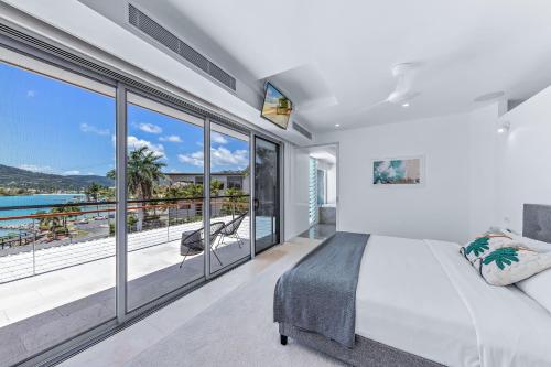 a bedroom with a large white bed and large windows at Whitsunday living on Hillcrest in Airlie Beach