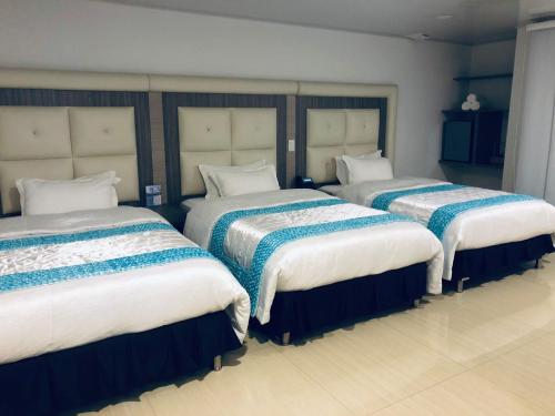a room with three beds with blue and white sheets at Hotel San Antonio Guarne in Guarne
