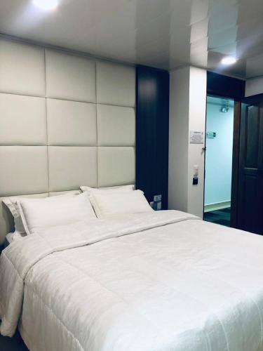 a large white bed with a large headboard in a room at Hotel San Antonio Guarne in Guarne