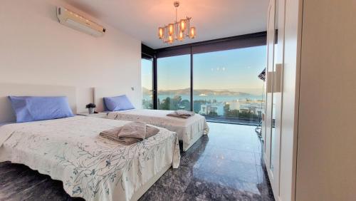 a bedroom with two beds and a large window at Villa Çimentepe in Bodrum City