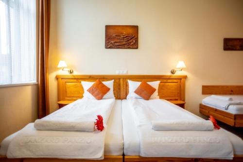 a bedroom with two beds with white sheets at Hotel Manzard Panzio in Budapest