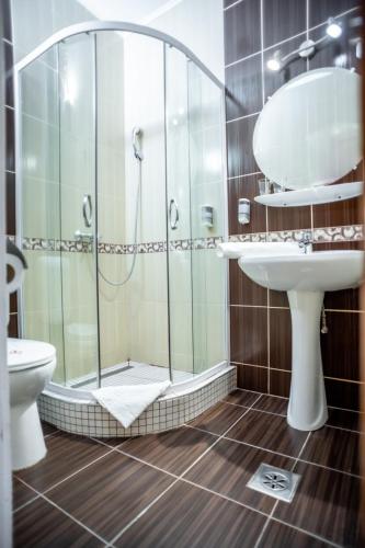 a bathroom with a shower and a sink and a toilet at Hotel Manzard Panzio in Budapest