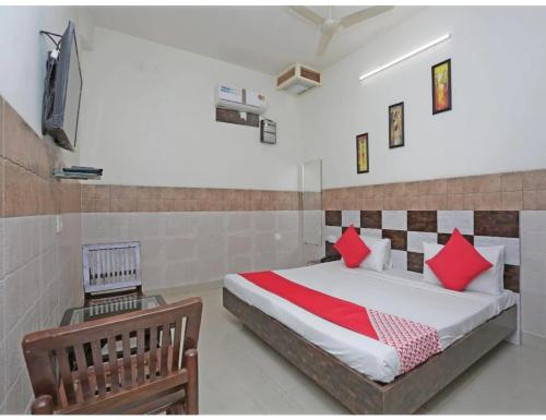 a bedroom with a bed with red pillows and a chair at Royal Comfort Cottage, Panipat in Pānīpat