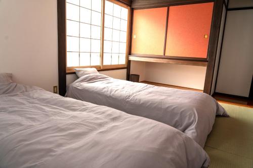 una camera con due letti e una finestra di Asagama House a Nozawa Onsen