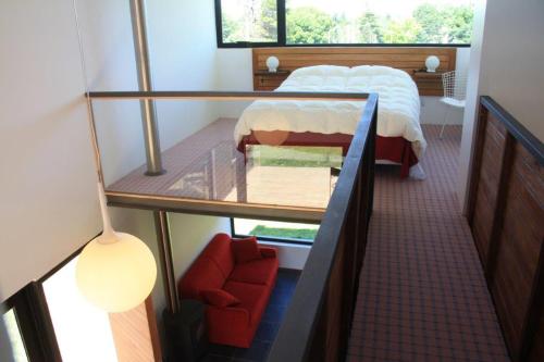 1 dormitorio pequeño con 1 cama y 1 silla roja en Hoyo 6 Rincón del Golf en Sierra de la Ventana