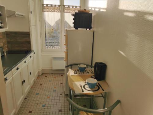 La cuisine est équipée d'une table, de chaises et d'un réfrigérateur. dans l'établissement VITTEL LOC'S - Le 215 Classé 4 étoiles, Spacieux et calme, à Vittel