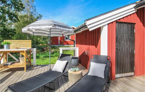 a deck with two chairs and an umbrella at Stunning Home In Figeholm With Kitchen in Figeholm