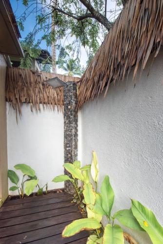 a building with a thatch roof and a wooden walkway at L'Osteria Luxe Beachfront B&B in General Luna
