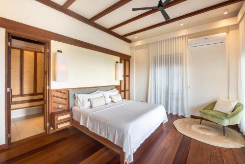 a bedroom with a white bed and a green chair at L'Osteria Luxe Beachfront B&B in General Luna