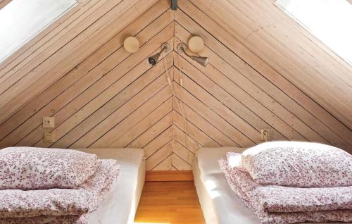 Duas camas num quarto com uma parede de madeira em 1 Bedroom Amazing Home In Frjestaden em Färjestaden