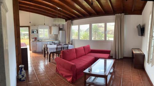 a living room with a red couch and a kitchen at Tantulia Las Tapias Tenerife in Puerto de la Cruz