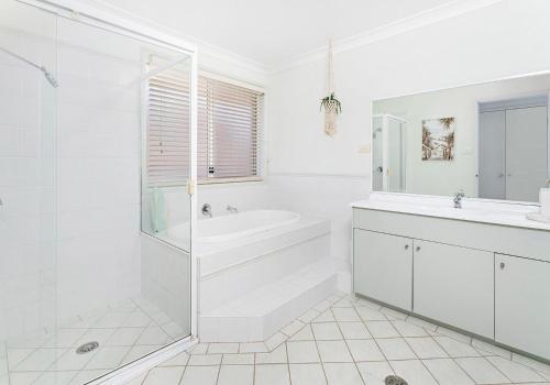 uma casa de banho branca com uma banheira e um lavatório em Drifters em Gerringong