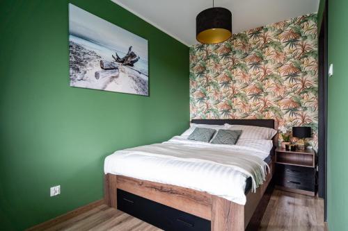 ein Schlafzimmer mit einem Bett mit einer grünen Wand in der Unterkunft Baltic Sun Muszelka in Sztutowo