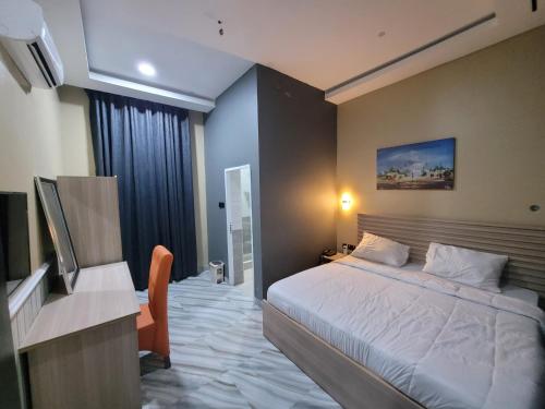 a bedroom with a bed and a desk and a television at The Charis Hotel & Suites in Port Harcourt