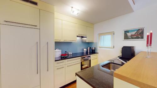 a kitchen with white cabinets and a sink at Palois Family Apartment Centre Lenzerheide in Lenzerheide