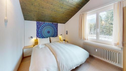a bedroom with a large white bed and a window at Palois Family Apartment Centre Lenzerheide in Lenzerheide