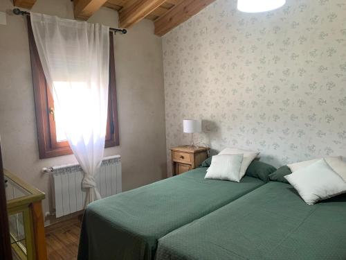 a bedroom with a green bed and a window at MolinoGrande del Duratón in San Miguel de Bernúy