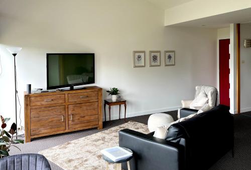 a living room with a flat screen tv on a wooden dresser at Cloud Nine Apartment @ Tamar Ridge in Grindelwald